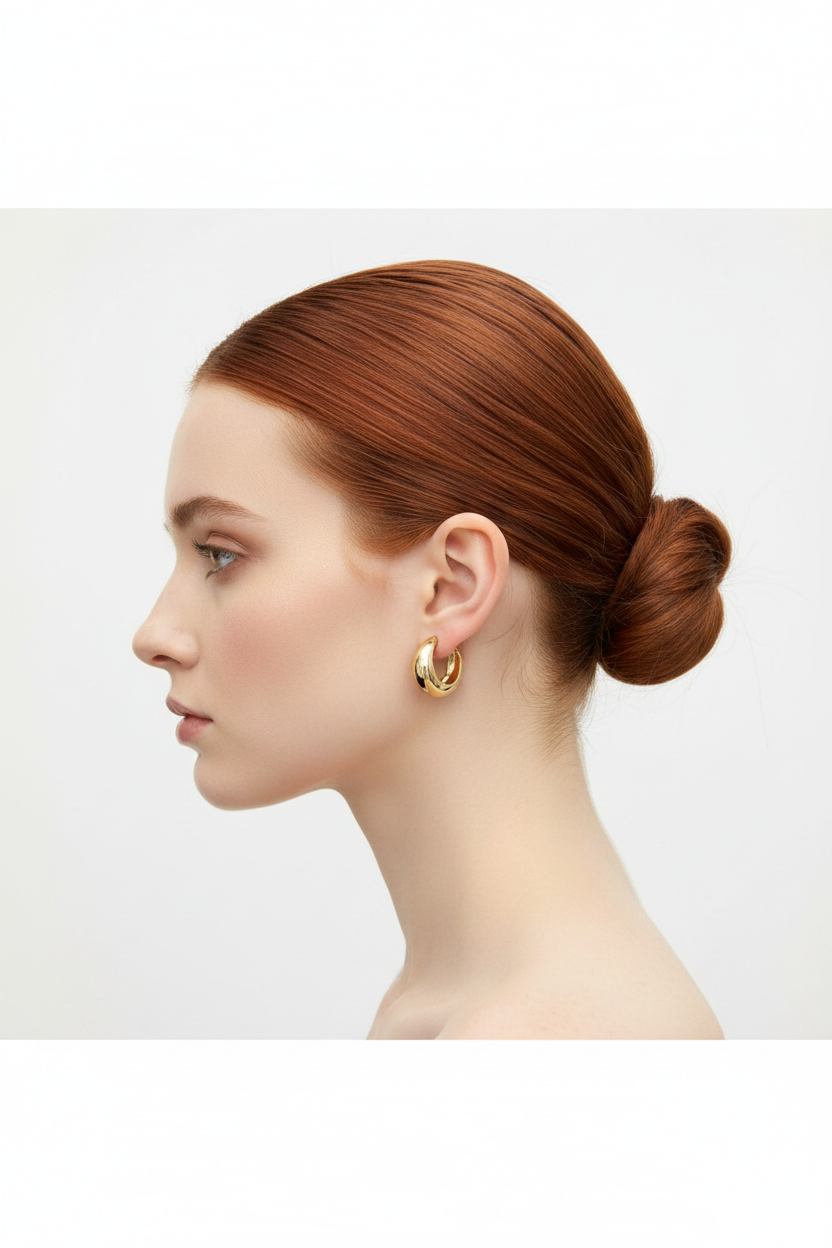 Redhead model with bun wearing chunky gold C-hoop earrings - side profile