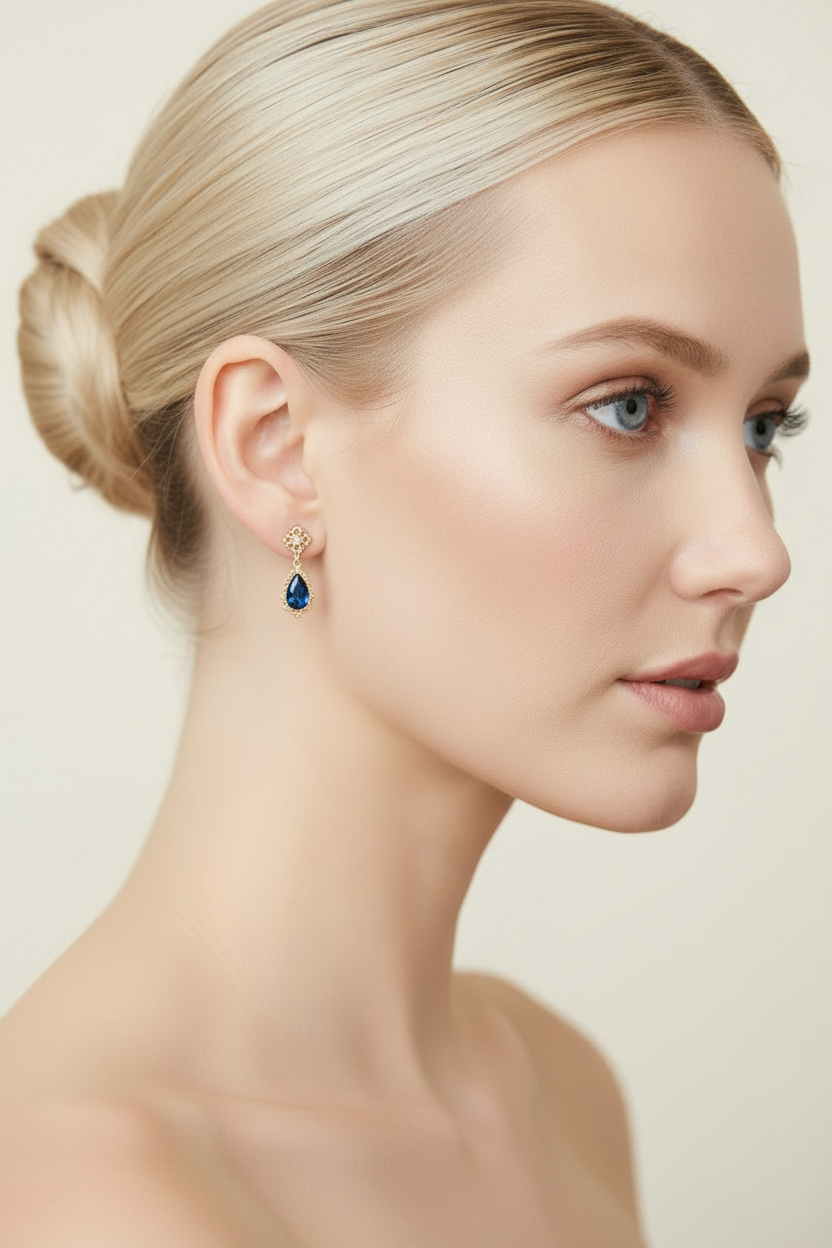 Nordic blonde model wearing delicate sapphire drop earrings - three quarter view bare shoulders