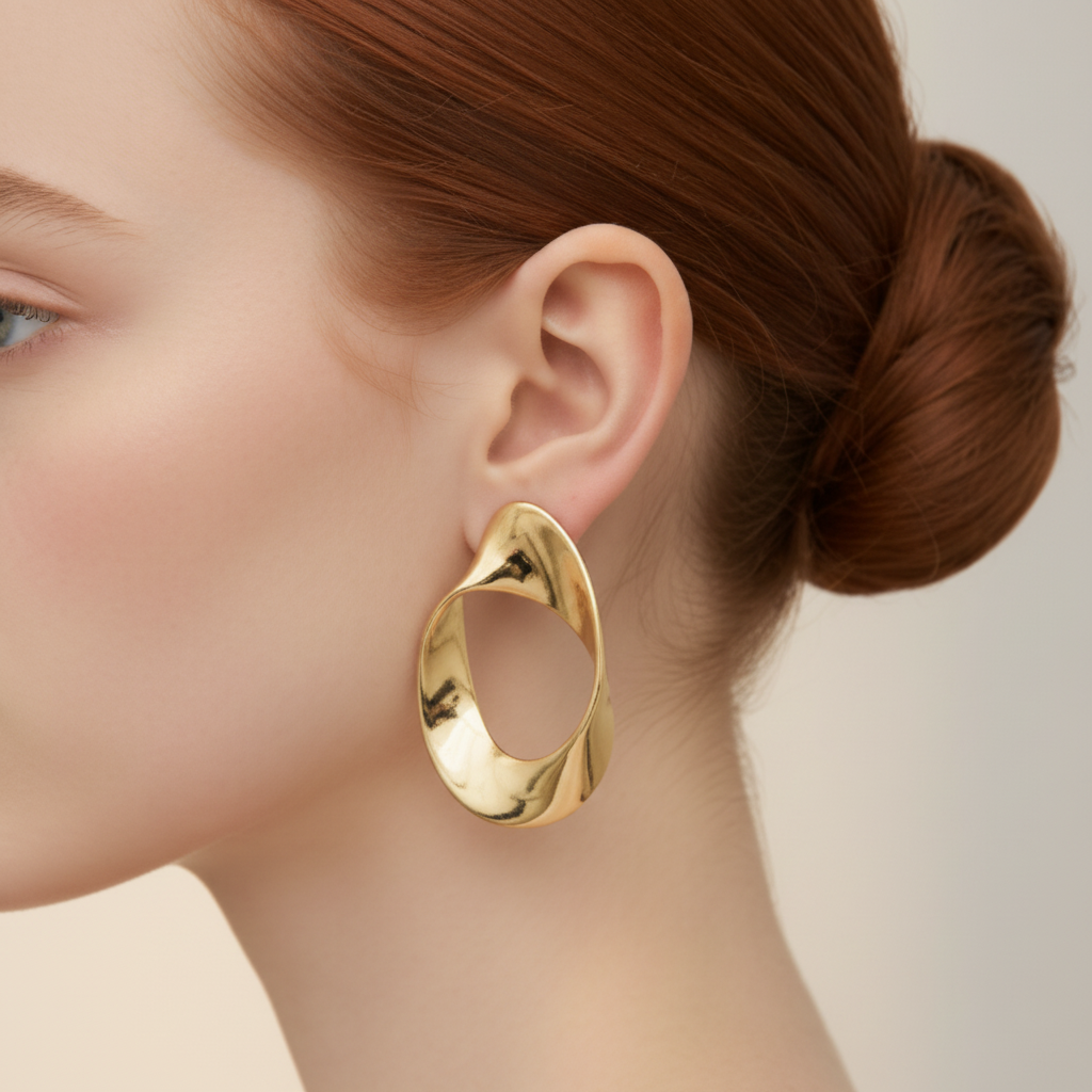 Close-up of model's ear wearing large gold twisted oval hoop earring