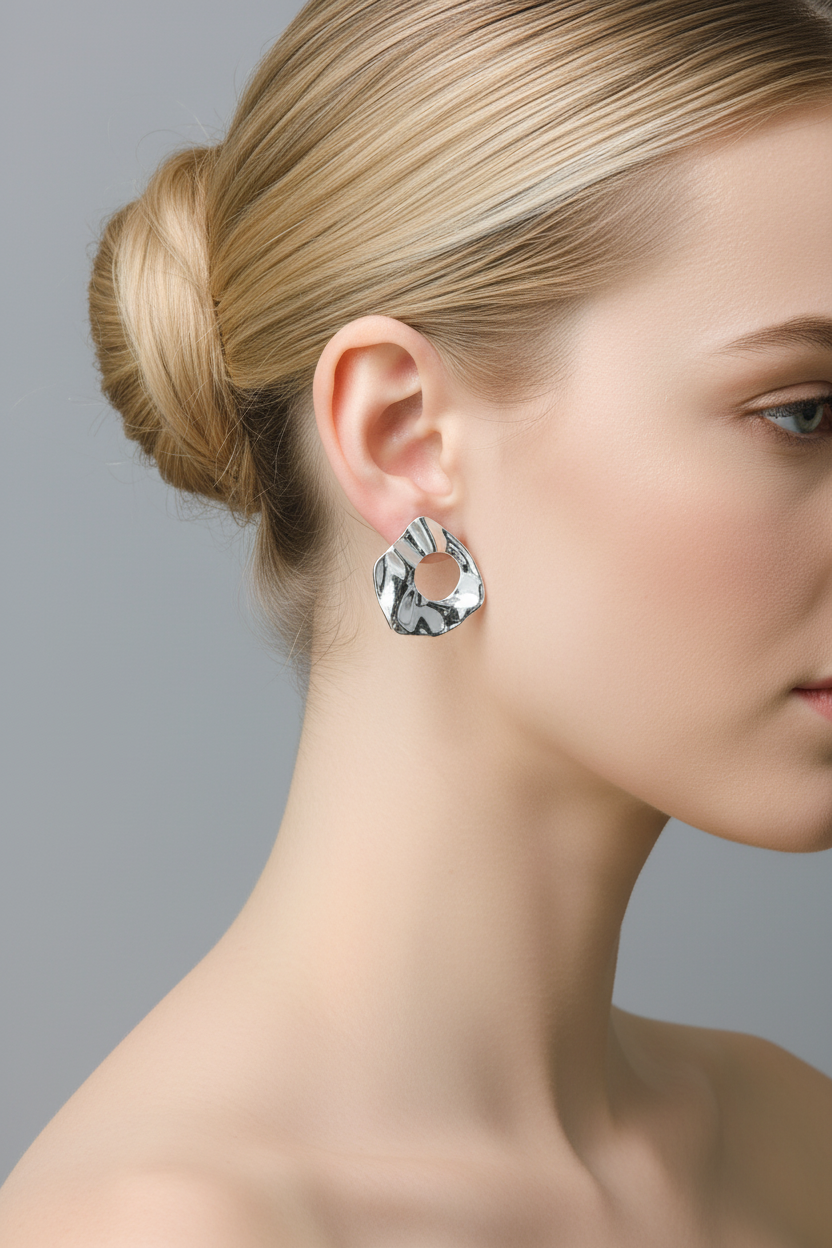 Blonde woman with ballerina bun wearing silver irregular waterdrop stud earrings, gray background