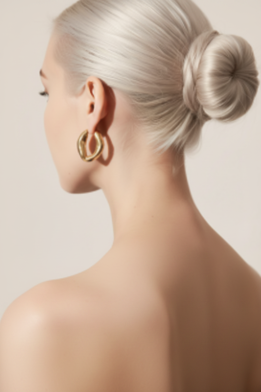Woman with platinum ballerina bun and bare shoulders wearing 18K gold hoop earrings