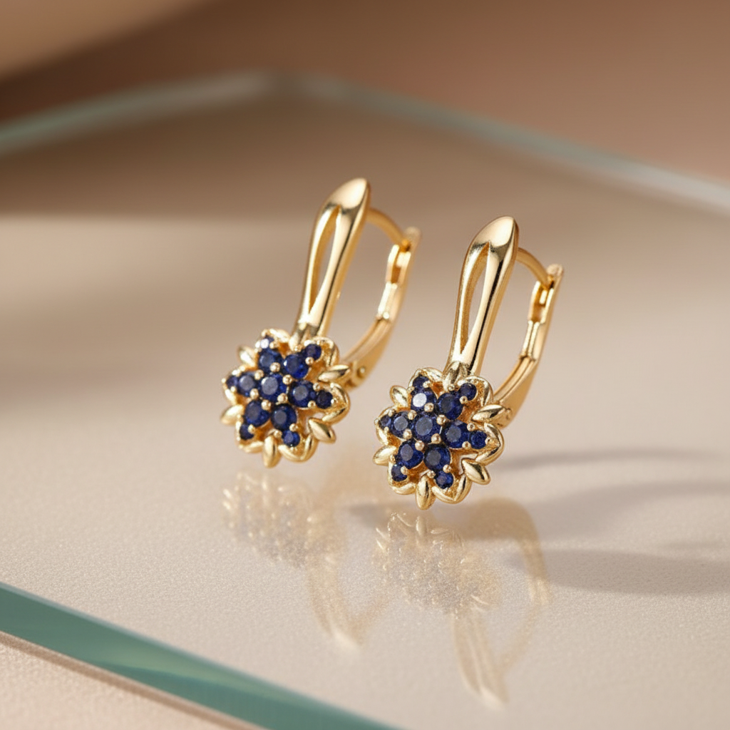 Gold sapphire sunflower drop earrings on glass surface