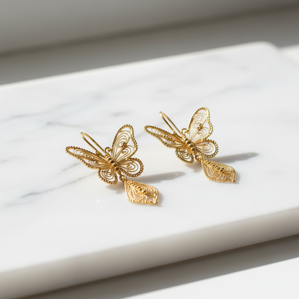 24K gold butterfly filigree dangle earrings on white marble