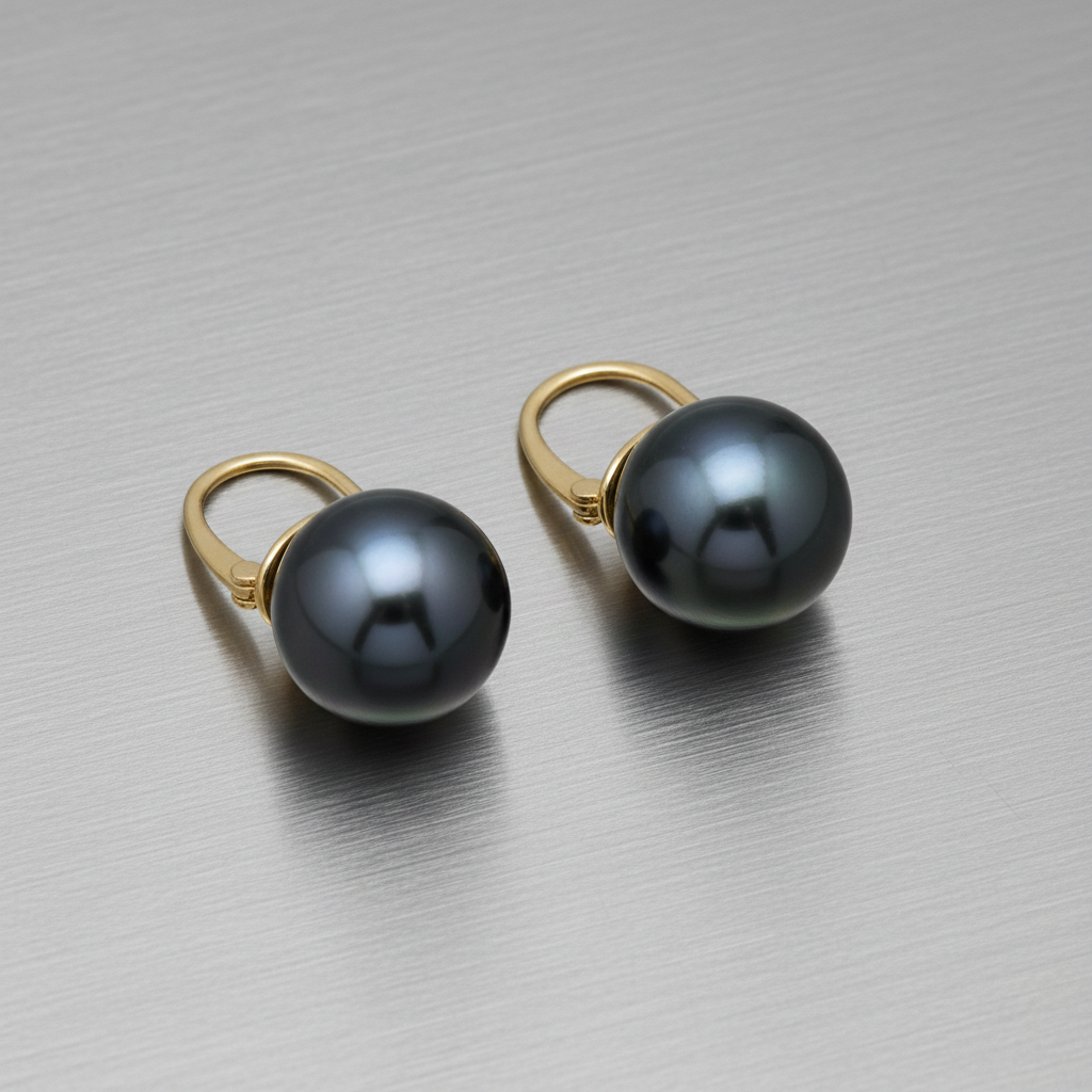 18K gold black Tahitian pearl ear clips on brushed steel surface
