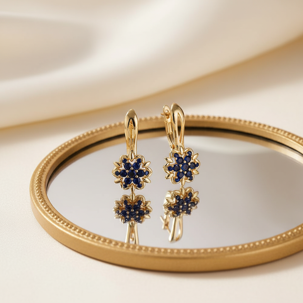Gold sapphire sunflower drop earrings in front of mirror
