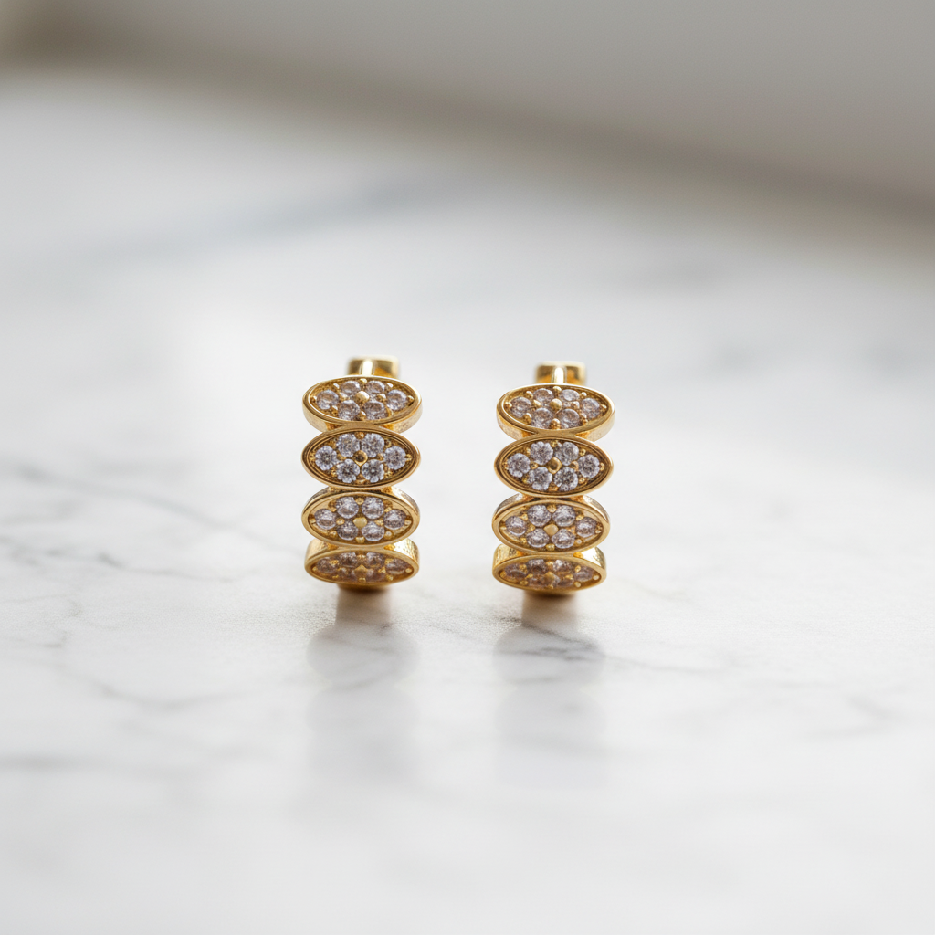 Gold zircon huggie earrings on white marble counter