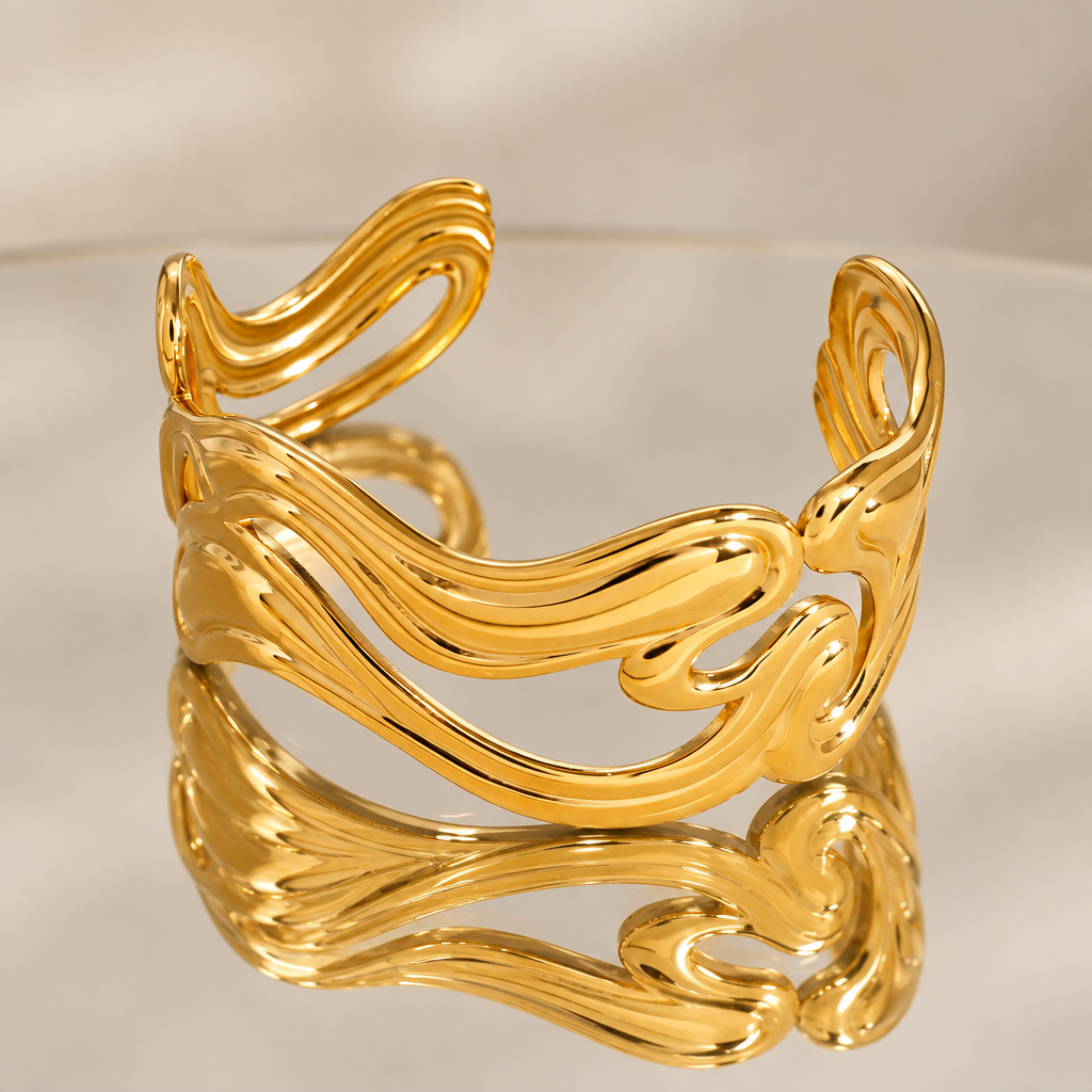 Anissa gold-tone wavy open cuff bracelet reflected in a mirror
