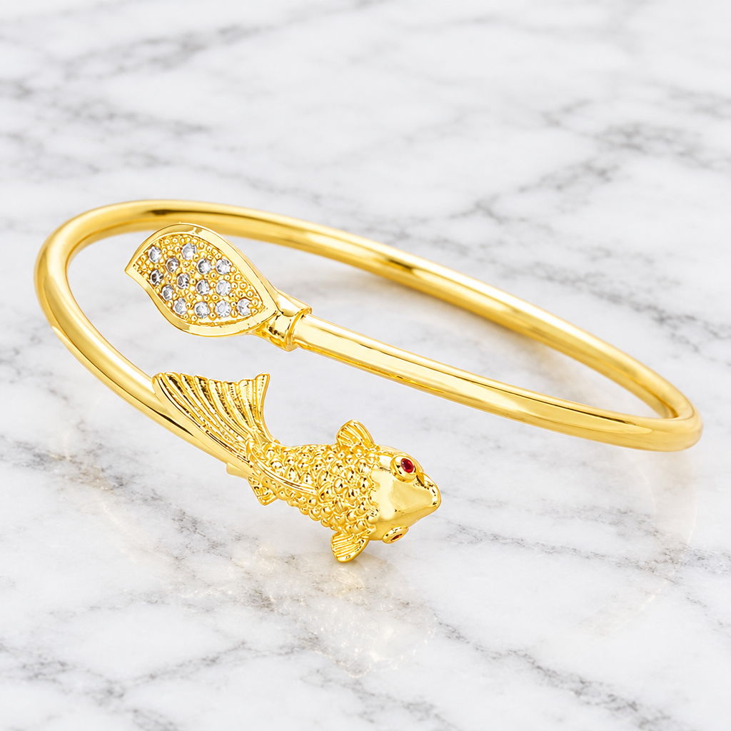 Gold-tone open fish and leaf cuff bracelet on white marble