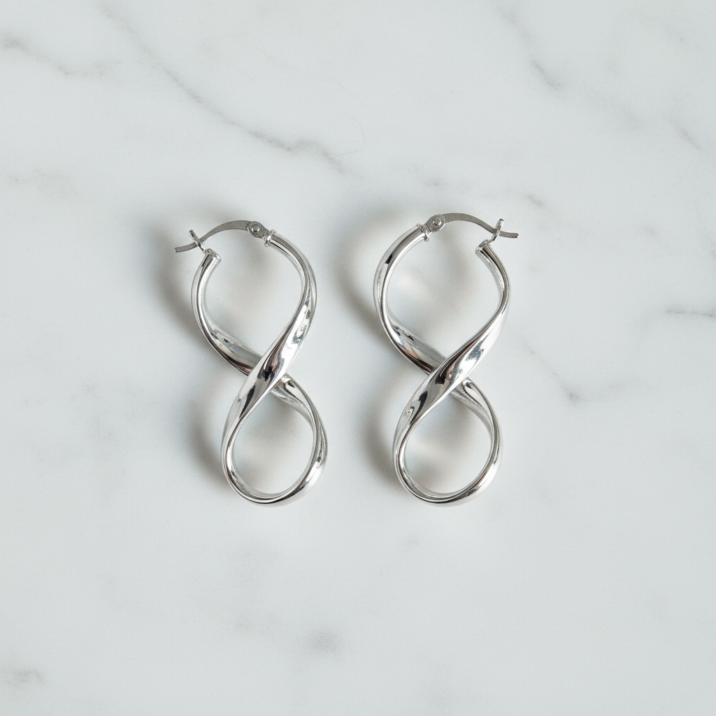 Silver infinity hoop earrings on white marble surface