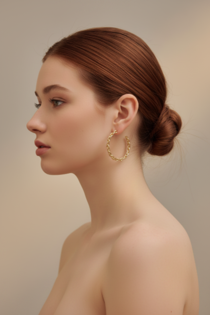 Model with bare shoulders wearing gold chain link hoop earrings