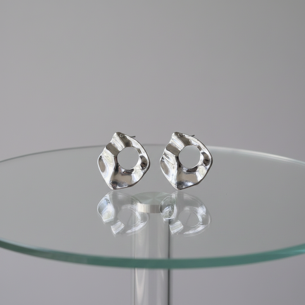 Silver irregular waterdrop stud earrings on glass table