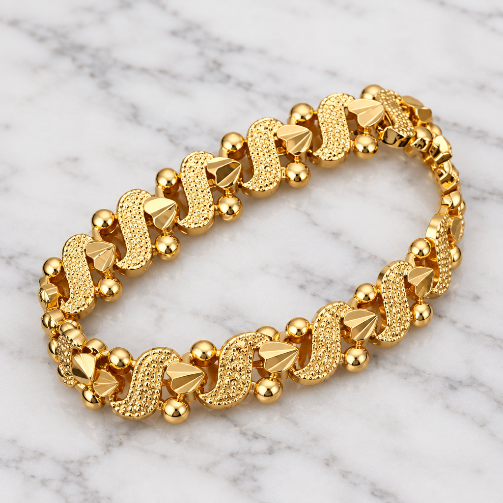 Gold-tone decorative bracelet with textured links on white marble