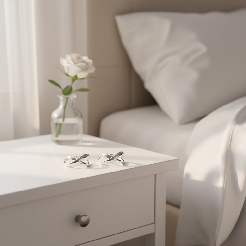 Silver infinity hoop earrings on bedside table
