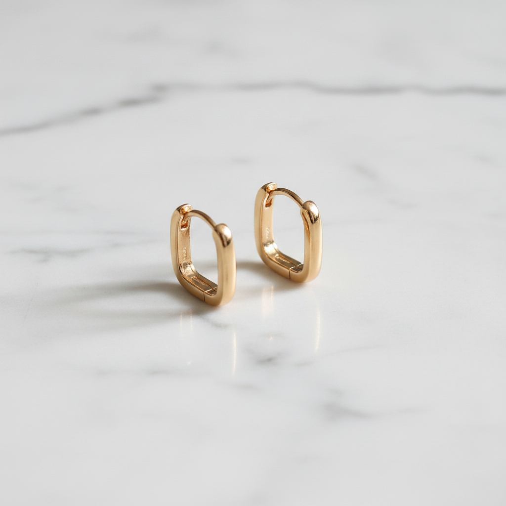 Gold geometric rectangular hoop earrings displayed on white marble counter