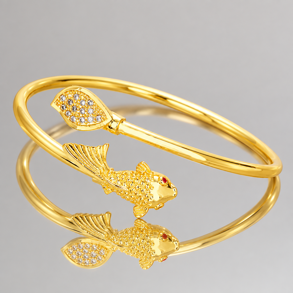 Gold-tone open fish and leaf cuff bracelet reflected in a mirror