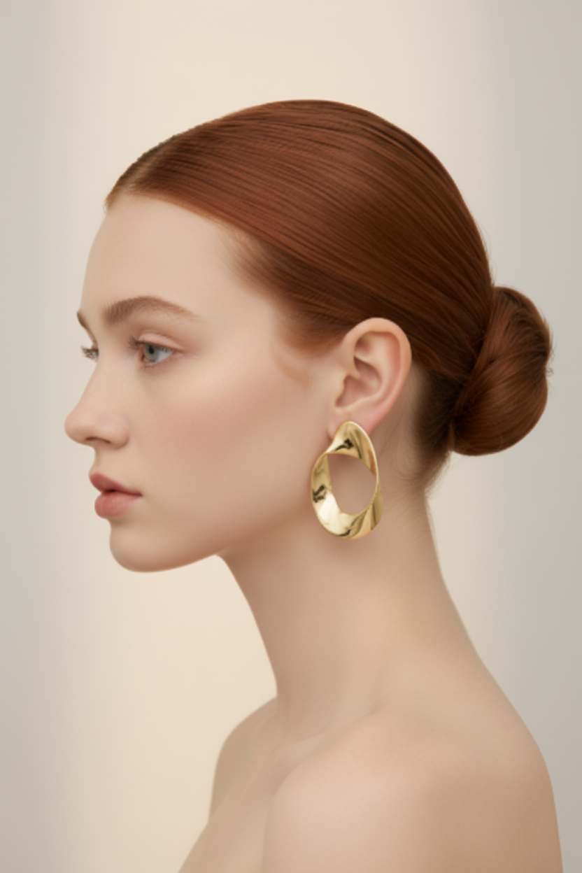 45-degree angle portrait model wearing large gold twisted oval hoop earrings