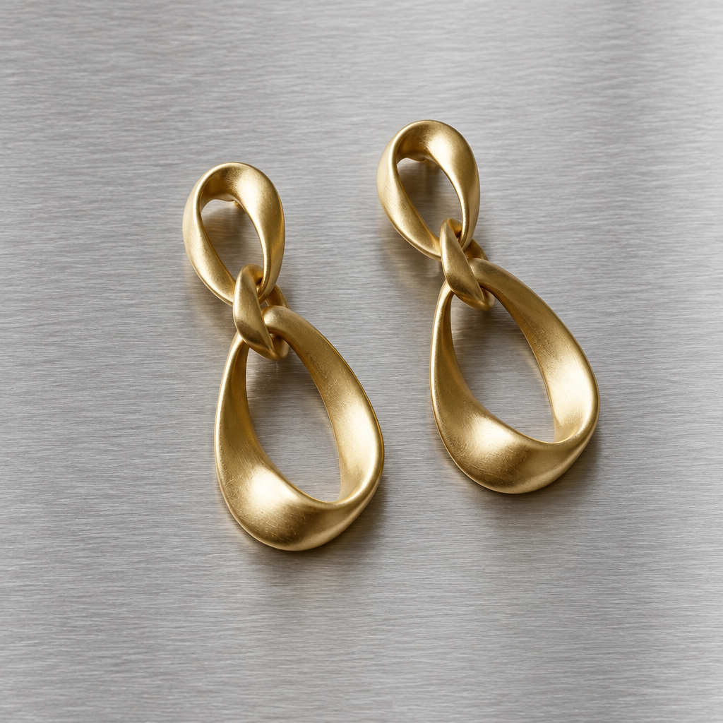 Pair of matte gold-tone geometric teardrop earrings on brushed steel