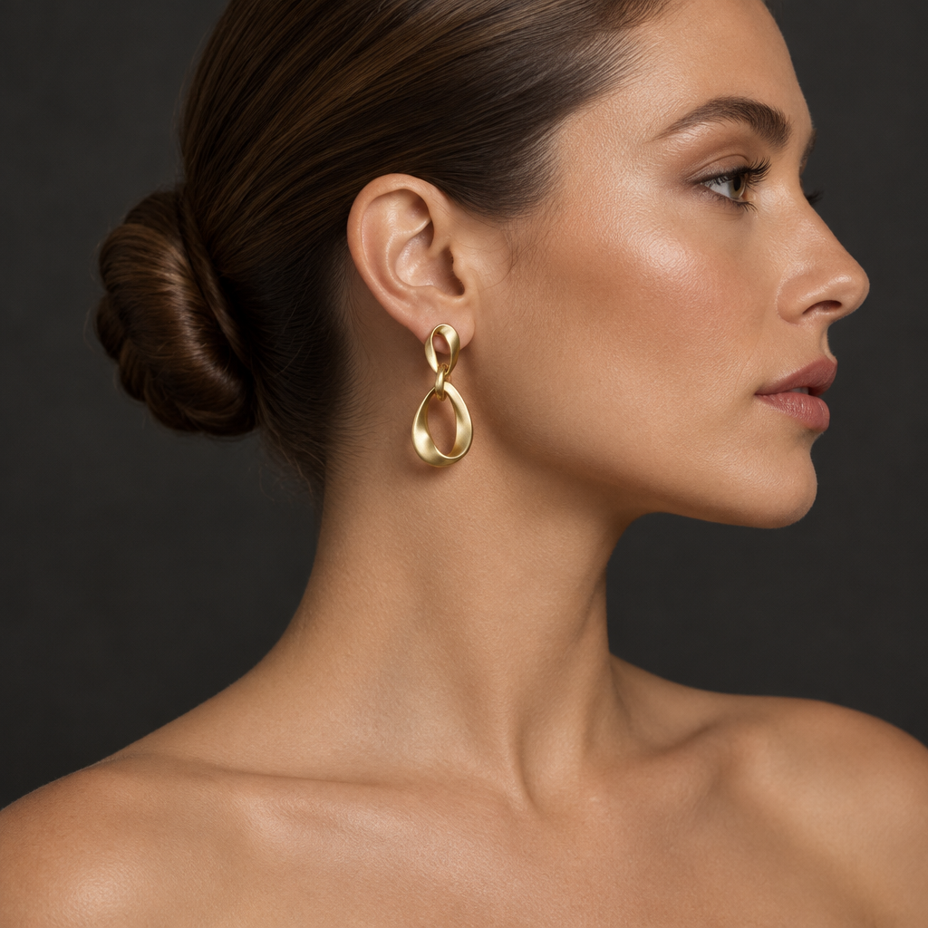 Opposite side profile of a woman with a ballerina bun wearing a matte gold-tone geometric earring