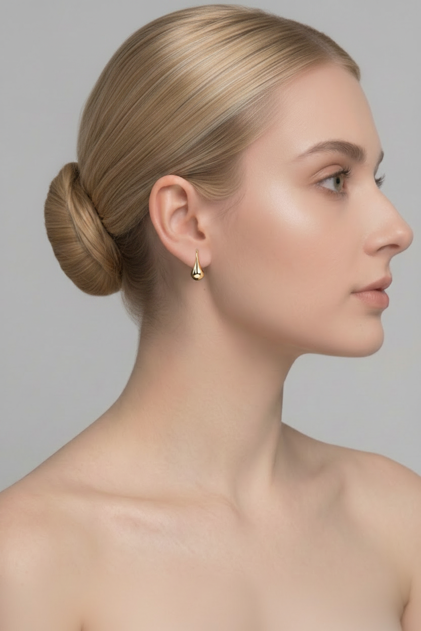 Blonde ballerina with bun wearing gold waterdrop drop earring, left side profile