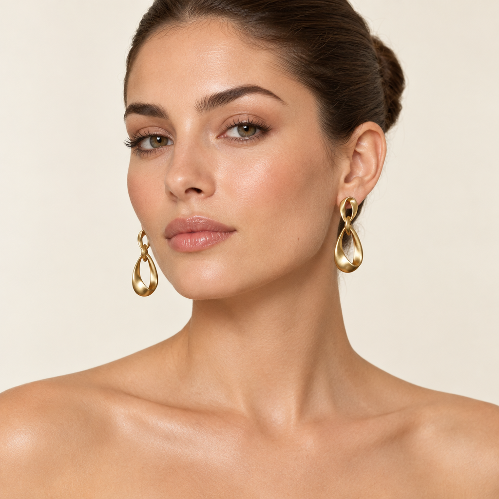 Three-quarter portrait of a woman with a ballerina bun wearing matte gold-tone geometric earrings
