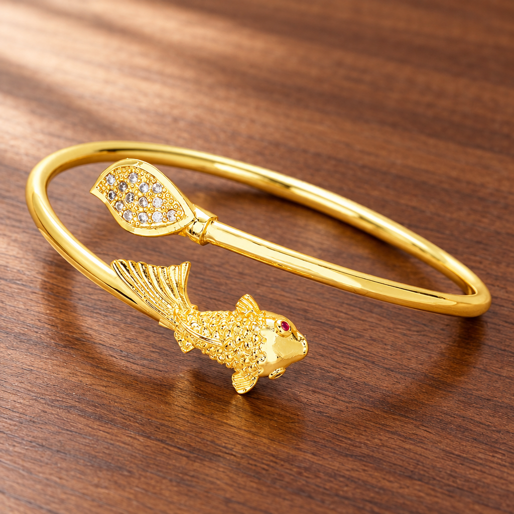 Gold-tone open fish and leaf cuff bracelet on a wooden table