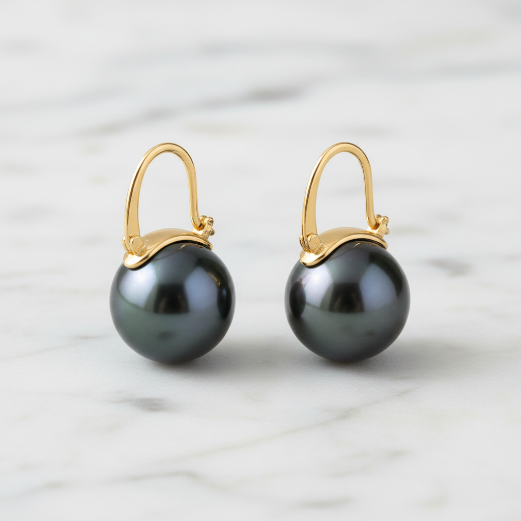 18K gold black Tahitian pearl ear clips on white marble