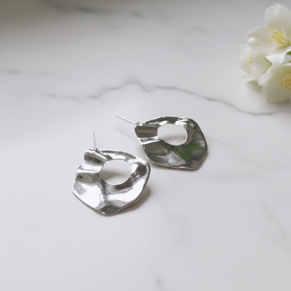 Silver irregular waterdrop stud earrings on white marble surface