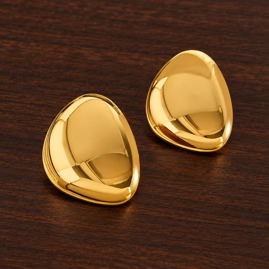 Pair of Carrie gold-tone rounded triangular earrings on dark wood