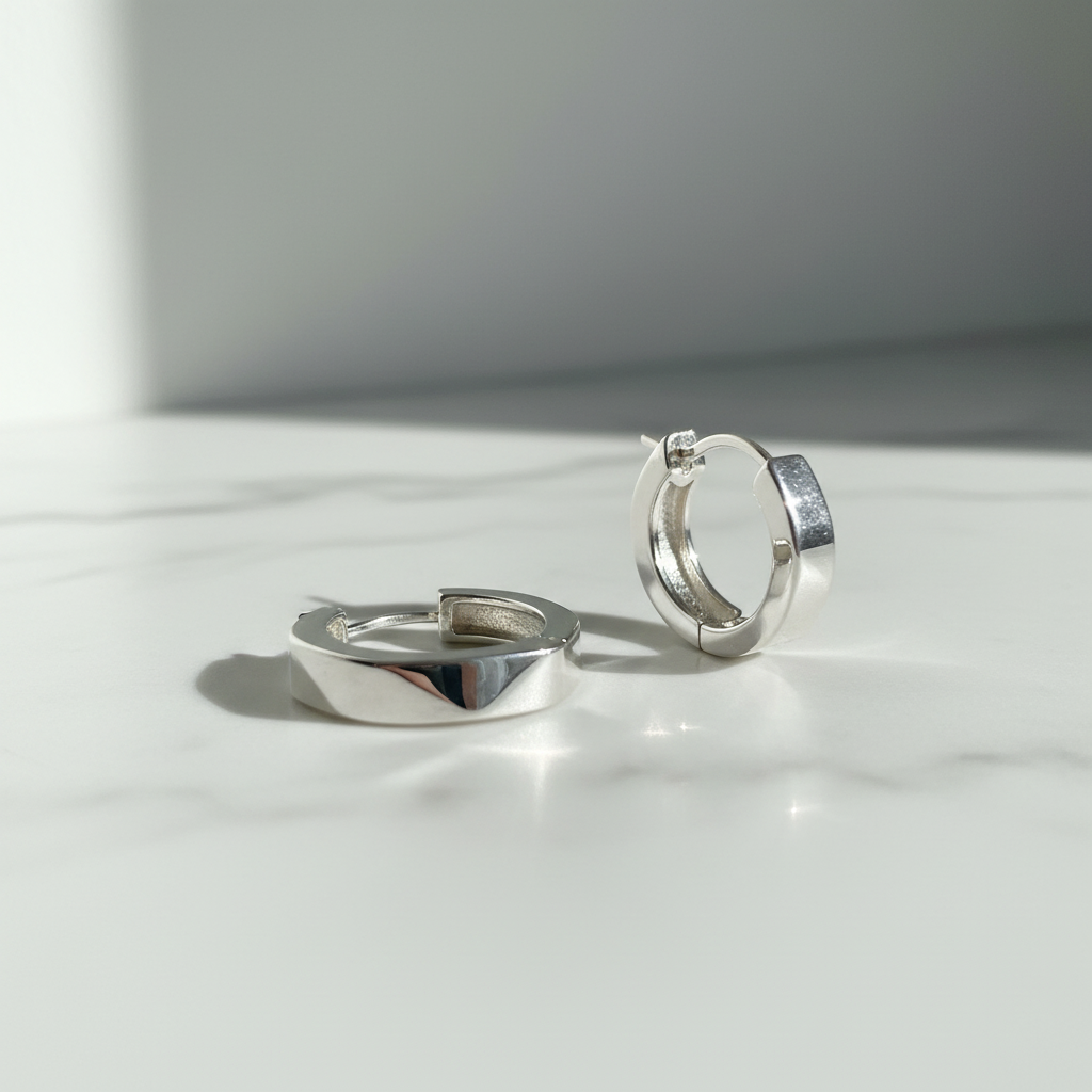 Silver geometric hoop earrings on white marble